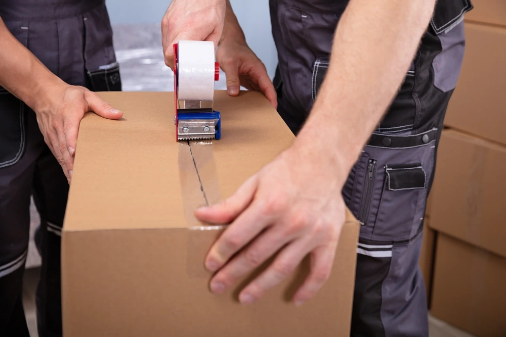 Movers taping cardboard box