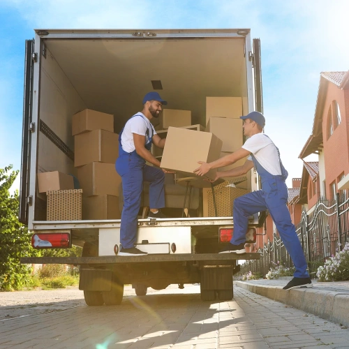 Two workers unloading boxes from moving truck on residential street